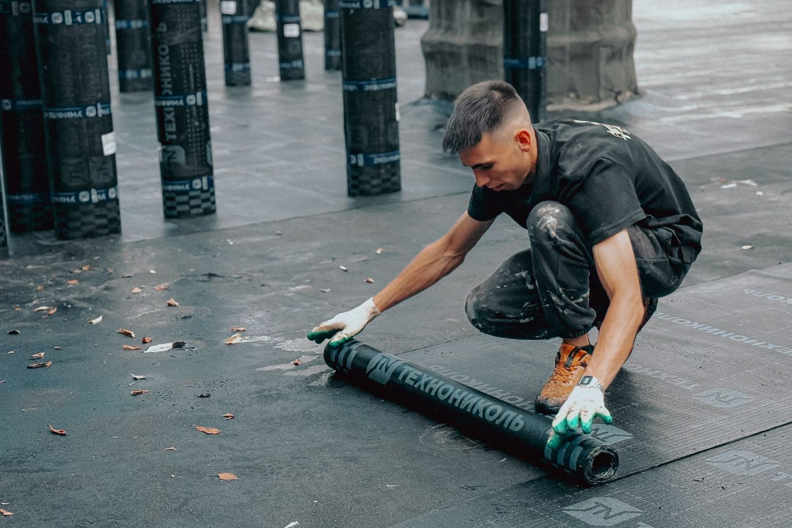 Roofer rolling out membrane on a commercial flat roof
