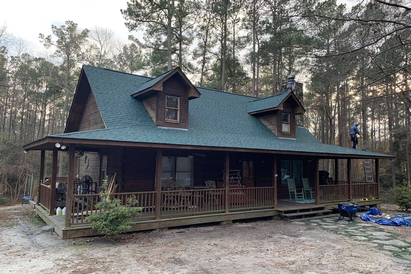 Melvin's Roofing crew finishing a green metal roof on a log cabin