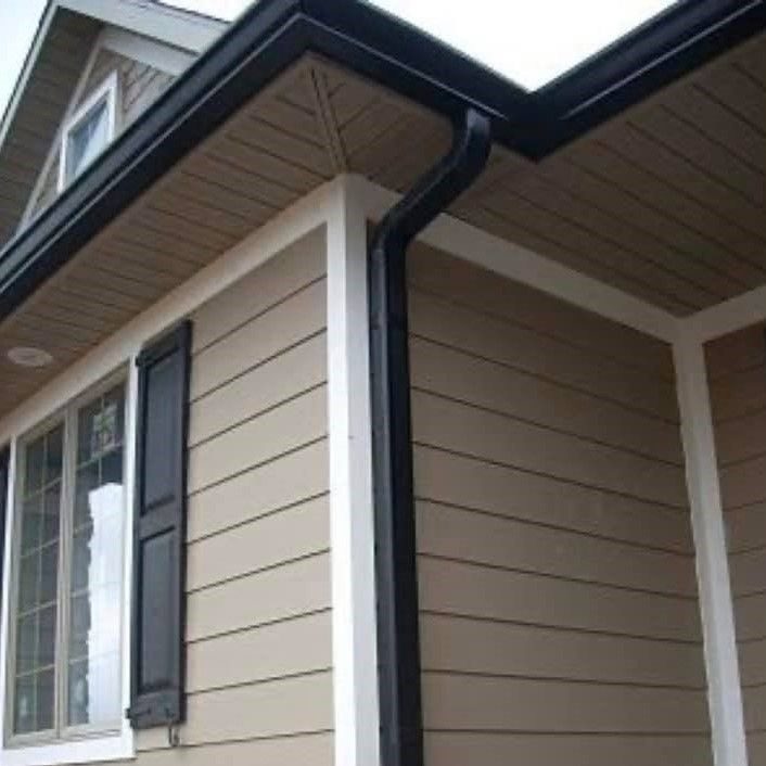 New black gutters and downspout on a home with tan siding