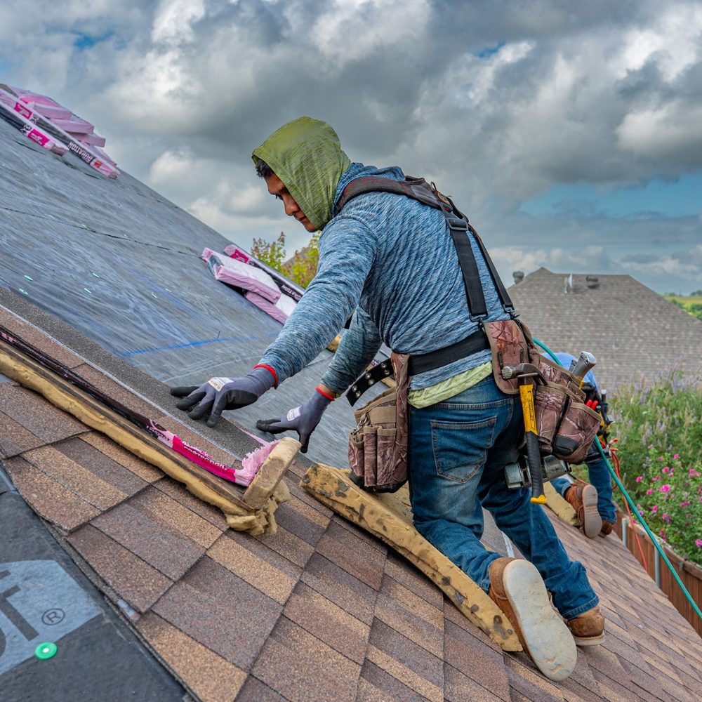 Roofer working on a steep shingle roof over new underlayment