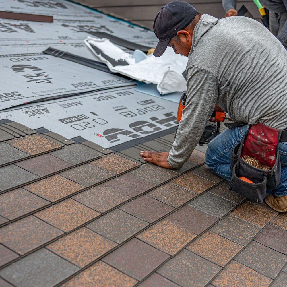 Roofer replacing a section of shingles on a sloped roof